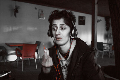 Young woman looking at broken headphones while sitting at cafe