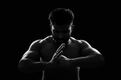 Young man gesturing over black background