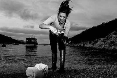 Full length of woman screaming while collecting sea urchins from lake against sky