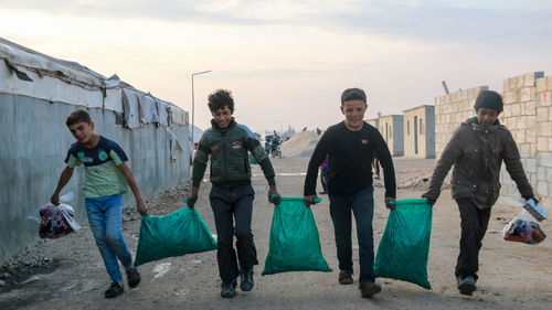 Full length of boys carrying supplies on street