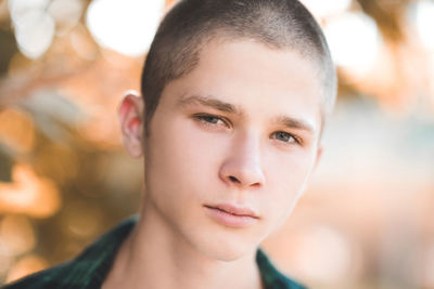Stylish teen boy 18-20 year old with blond short haircut outdoors closeup. looking at camera. 