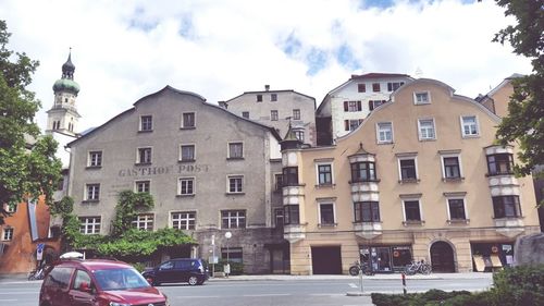 Cars on road by buildings against sky