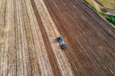 Tractor plows ground on cultivated farm field