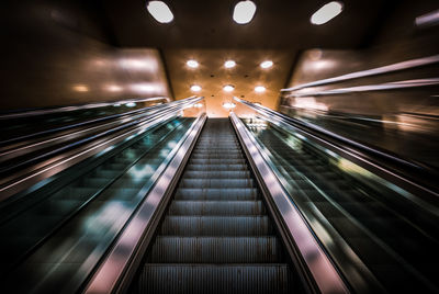 Light trails on illuminated escalator at night