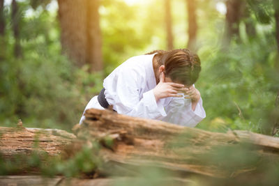 Side view of woman sitting on wood