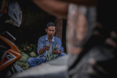 Mid adult man holding spring onion at vegetable market