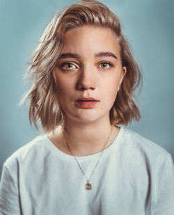 Portrait of young woman crying against gray background