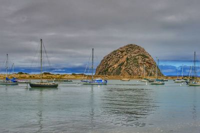 Sailboats moored in sea against sky