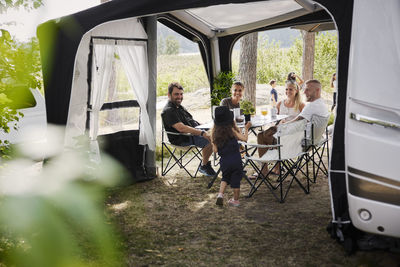 Friends with children relaxing under garden gazebo