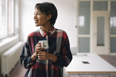 Smiling young woman holding cup