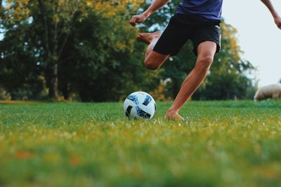 Low section of people playing soccer ball on field