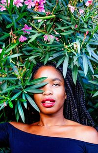 Portrait of young woman standing against plants