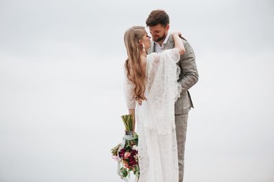 Bride and bridegroom standing against clear sky