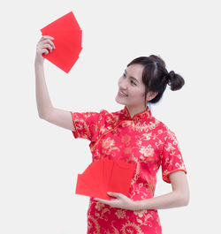 Smiling young woman holding umbrella against white background
