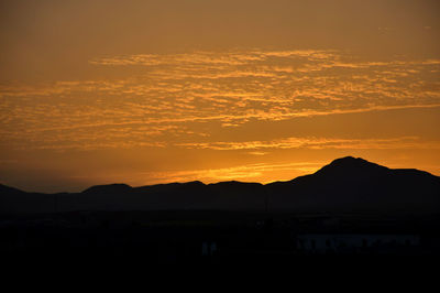 Scenic view of silhouette mountains against romantic sky at sunset