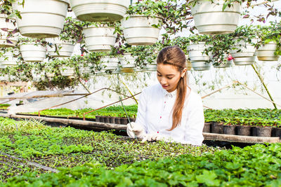 Young woman smiling while standing against plants