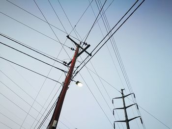 Low angle view of electricity pylon against clear sky