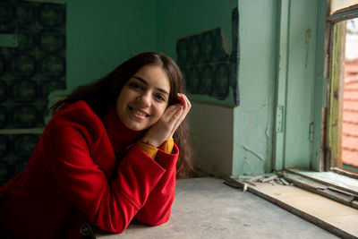 Portrait of smiling young woman sitting on window