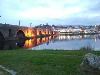 Illuminated bridge over river against sky