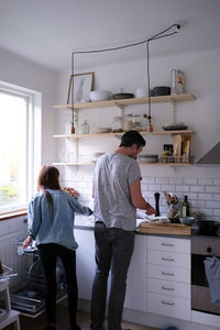 Rear view of man and woman working in kitchen at home