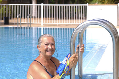 Portrait of smiling senior woman standing in swimming pool