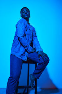 Portrait of woman sitting on chair in front of wall