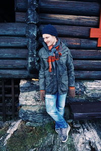 Full length of smiling man leaning on barn