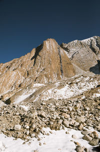 Low angle view of snowcapped mountain against clear blue sky