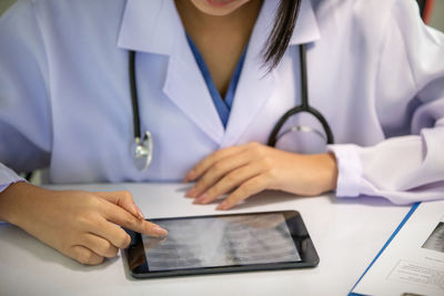 Midsection of man using mobile phone on table