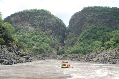 Boat on river by mountain against sky