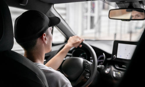Side view of man driving car