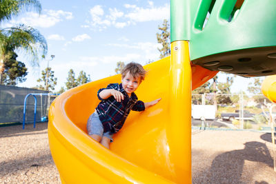 Modern colorful kids playground - swings, slides, steps and ladders. little boy on swing and slide.