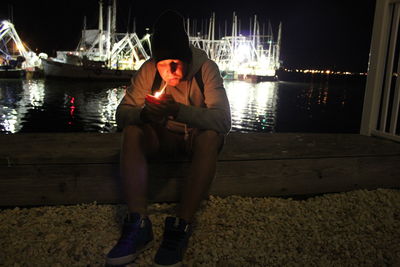 Full length of man smoking while sitting at harbor