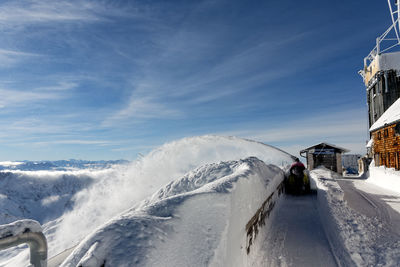 Man standing at snow covered mountains against sky