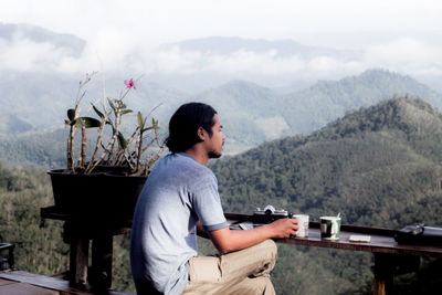 Side view of young man looking at mountains