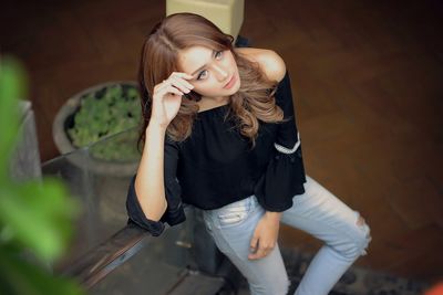 Portrait of young woman standing against wall