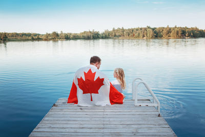 Rear view of couple on pier at lake