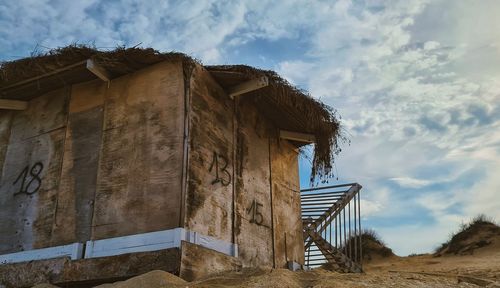Low angle view of old house on field against sky