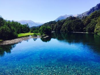 Scenic view of swimming pool by lake against clear blue sky