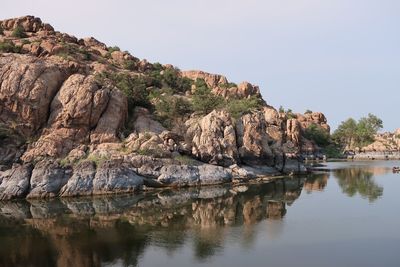 Rock formations by lake against sky