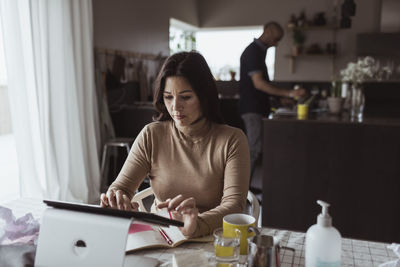Female entrepreneur working on digital tablet at home