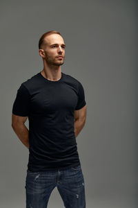 Portrait of young man standing against black background