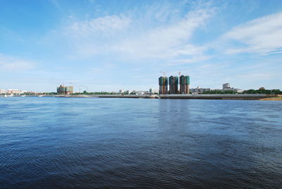 View of buildings by river against cloudy sky