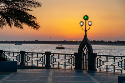 Silhouette palm trees by sea against sky during sunset