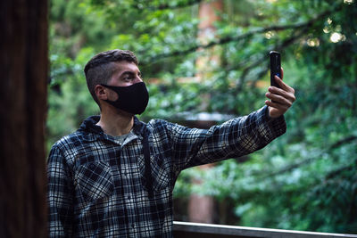 Man wearing mask taking selfie in forest