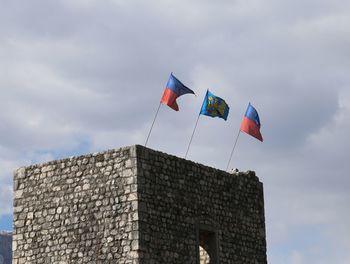 Low angle view of flag against building against sky