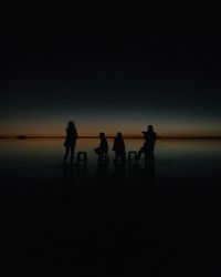 Silhouette people on beach against clear sky at night