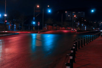 Empty road along illuminated street lights at night