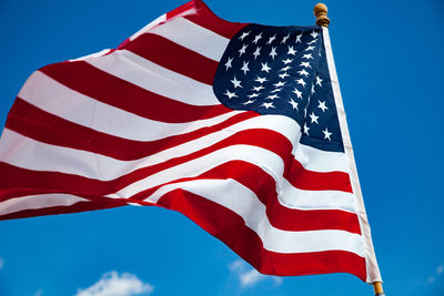 Low angle view of american flag against blue sky