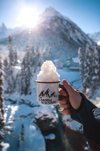 Mug with snow in hand on a background of mountains